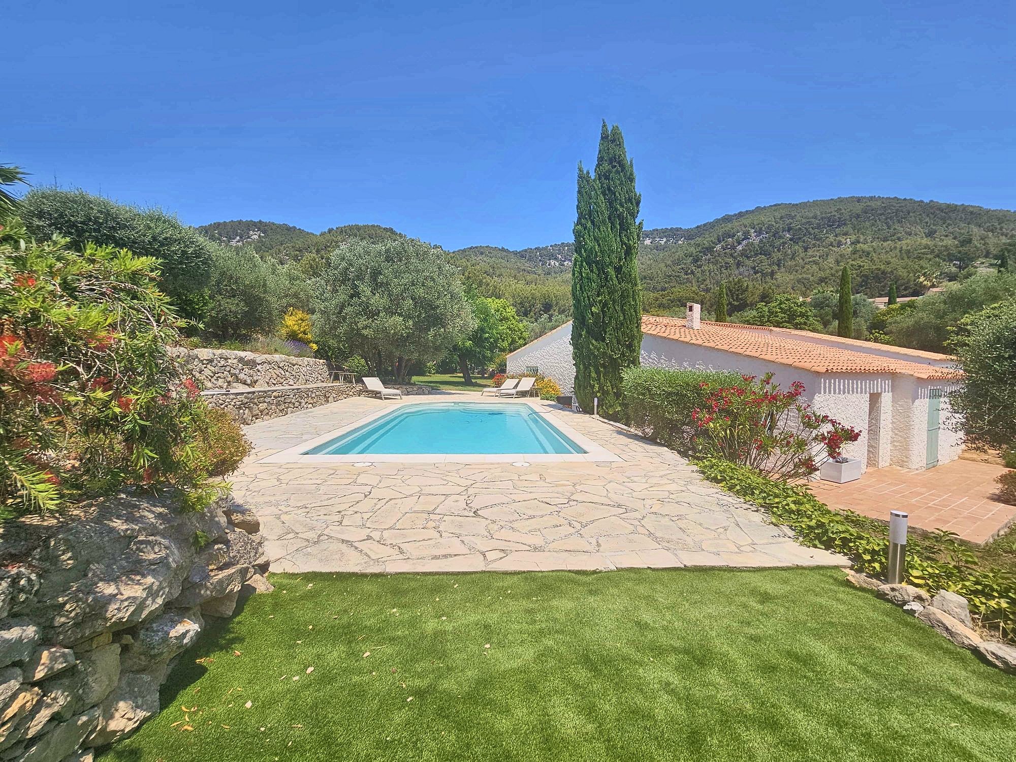 La piscine chauffée, sa plage en pierre et les cyprès
